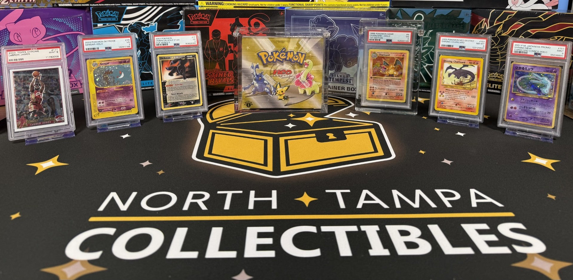 Neo Genesis booster box and graded Pokémon cards displayed on the North Tampa Collectibles mat